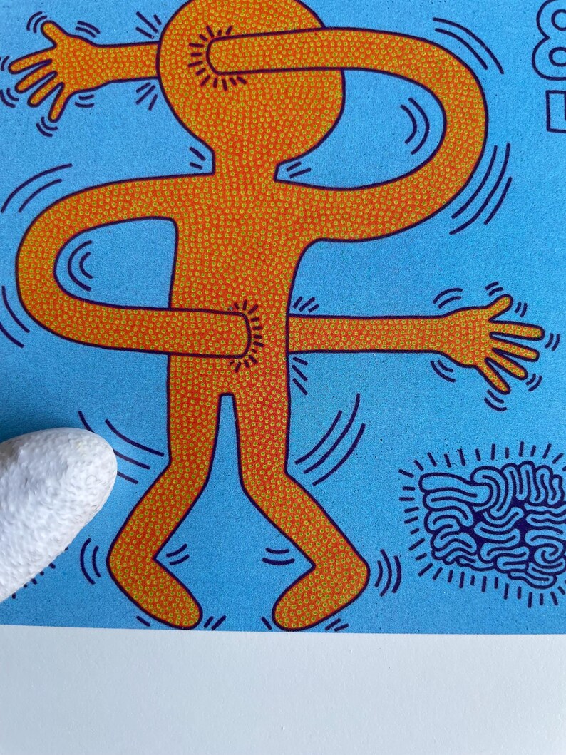 K&ouml;nnte beinhalten: Eine leuchtend orangefarbene Figur mit einem gepunkteten Muster, die in Schwarz umrandet ist, mit zwei Armen und Beinen, ist auf einem hellblauen Hintergrund dargestellt. Die Arme der Figur sind gebogen und miteinander verbunden, um einen Kreis zu bilden. Die Figur ist von schwarzen Linien umgeben, die einen wirbelnden Effekt erzeugen. Eine blaue, gehirn&auml;hnliche Form befindet sich in der unteren rechten Ecke des Bildes.