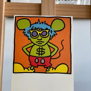 K&ouml;nnte beinhalten: Ein farbenfroher Druck eines Comic-Charakters mit blauen Haaren, gelber Sonnenbrille und einem Dollarzeichen auf der Brust. Der Charakter tr&auml;gt rote Shorts und hat gro&szlig;e gelbe F&uuml;&szlig;e. Der Hintergrund ist orange.