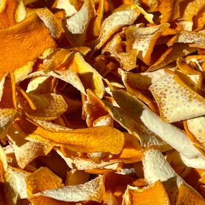 May include: Close-up of dried orange peels, showcasing vibrant orange and off-white colors. The peels have a textured surface and varying shapes, creating a natural, organic aesthetic. The image highlights the details of the dried citrus fruit.