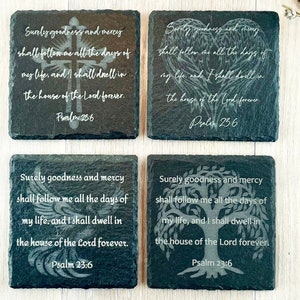 May include: Set of four black slate coasters with white engraved text and images. The text reads "Surely goodness and mercy shall follow me all the days of my life, and I shall dwell in the house of the Lord forever. Psalm 23:6". The images are a cross, a pair of wings, a tree, and a tree with roots.