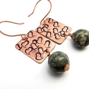 May include: Copper earrings with a heart pattern and green stone beads.