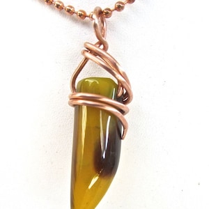 May include: A copper wire wrapped pendant featuring a yellow and brown tiger's eye stone. The pendant is attached to a copper chain.