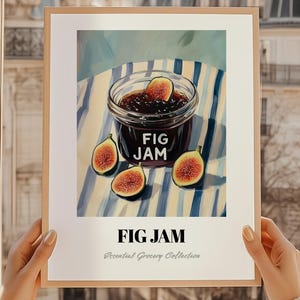 Può includere: Una stampa incorniciata con un barattolo di marmellata di fichi e fichi a fette. Il testo "FIG JAM" è ben visibile, con "Essential Grocery Collection" sotto. Lo sfondo presenta strisce blu e bianche.