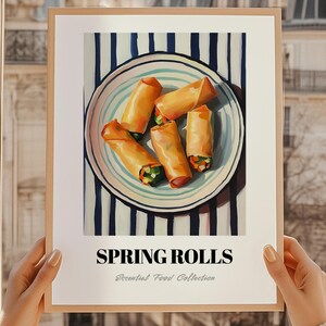 Può includere: Una stampa incorniciata con involtini primavera su un piatto. Gli involtini primavera sono marroni dorati e ripieni di verdure. Il piatto ha strisce blu e verdi, su uno sfondo di strisce verticali blu e bianche. Il testo recita "SPRING ROLLS".
