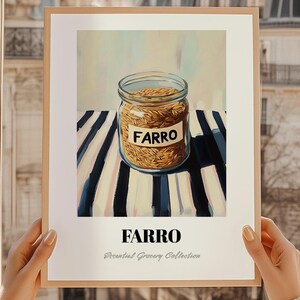 May include: A framed print showing a jar of farro on a striped surface. The jar has a label that reads "FARRO". Below the jar, the word "FARRO" is repeated in a larger font, with "Essential Grocery Collection" below it.