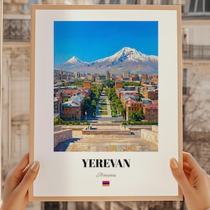 Peut inclure: Une impression encadrée représentant la ville de Erevan, en Arménie, avec une chaîne de montagnes en arrière-plan sous un ciel bleu clair. L'image met en valeur l'architecture urbaine et la verdure. Le nom de la ville et le drapeau arménien sont inclus.