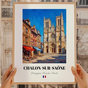 Op de afbeelding: Een ingelijste kunstdruk van Chalon-sur-Saône, Frankrijk, met een levendig olieverfschilderij van een kathedraal en gebouwen met rode en blauwe luifels. De print bevat de naam van de stad en de regio, met de Franse vlag onderaan.