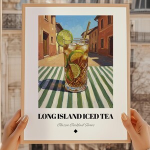 Könnte beinhalten: Ein gerahmter Druck eines Long Island Iced Tea Cocktails. Das Kunstwerk zeigt ein hohes Glas gefüllt mit Eis, Limettenscheiben und einem Strohhalm, vor dem Hintergrund einer europäischen Straßenszene. Der Text "LONG ISLAND ICED TEA" ist unten zu sehen.