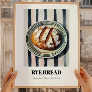 Könnte beinhalten: Gerahmter Kunstdruck mit Roggenbrot auf einem Teller vor gestreiftem Hintergrund. Das Brot ist goldbraun, mit weißem Mehl bestäubt und eingeschnitten. Text: "RYE BREAD" und "Essential Food Collection".