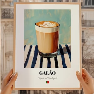 Może przedstawiać: Oprawiony wydruk artystyczny przedstawiający Galão, portugalski napój kawowy. Obraz przedstawia szklankę kawy z pianką na wierzchu, na tle niebiesko-białych pasków. Słowo "GALÃO" jest wydrukowane poniżej.