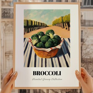 Könnte beinhalten: Gerahmter Kunstdruck mit Brokkoli in einem Weidenkorb. Der Korb steht auf einer gestreiften Oberfläche, mit Bäumen und blauem Himmel im Hintergrund. Unter dem Bild steht das Wort "BROCCOLI".