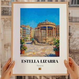 May include: A framed art print showcasing a colourful painting of Estella-Lizarra, Spain. The artwork depicts a plaza with a domed structure, surrounded by buildings under a bright blue sky. The print includes the text "ESTELLA-LIZARRA" and the Spanish flag.