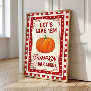 Könnte beinhalten: Ein gerahmter Druck mit Vintage-Design. Das Kunstwerk zeigt einen leuchtend orangefarbenen Kürbis in der Mitte mit dem Text "LET'S GIVE 'EM PUMPKIN TO TALK ABOUT" in einer dekorativen Schriftart. Der Rand ist rot und weiß mit Sternakzenten.