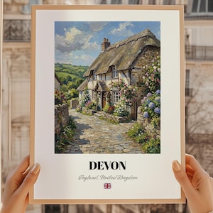 Può includere: Una stampa incorniciata di un cottage pittoresco nel Devon, in Inghilterra, con tetto di paglia e muri in pietra, circondato da fiori colorati. La stampa include il testo "DEVON" e "England, United Kingdom" con una bandiera britannica.