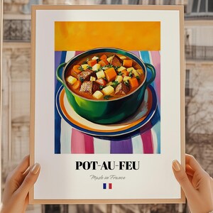 Puede incluir: Una impresión enmarcada que presenta una vibrante ilustración de Pot-au-Feu, un guiso francés tradicional. El guiso está en una olla verde sobre un plato con rayas coloridas. La impresión incluye el texto "POT-AU-FEU" y "Made in France" con la bandera francesa.