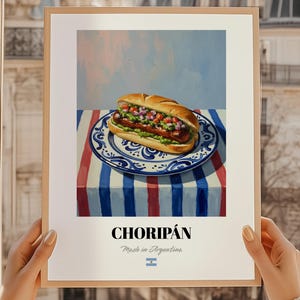 May include: A framed print depicting a choripán sandwich, a South American street food, on a patterned plate. The sandwich is filled with sausage and a fresh relish. The plate sits on a striped tablecloth. The print includes the word "CHORIPÁN" and "Made in Argentina".