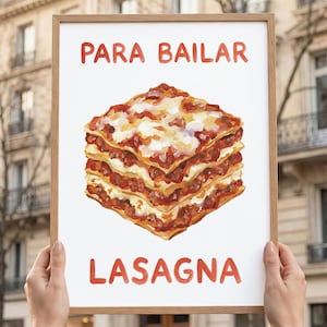 May include: A framed print featuring a watercolor painting of a lasagna. The words "PARA BAILAR" and "LASAGNA" are written in red above and below the lasagna illustration. The frame is made of light brown wood.