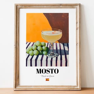 May include: Framed art print featuring a cocktail in a coupe glass, a bunch of green grapes, and the word "MOSTO" with "Made in Spain" below it. The background has orange and brown hues, with a striped table. The Spanish flag is at the bottom.