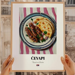 May include: A framed print featuring a plate of ćevapi, a Serbian dish, with flatbread and onions. The plate is on a pink and white striped background. The text "ĆEVAPI Made in Serbia" is at the bottom.