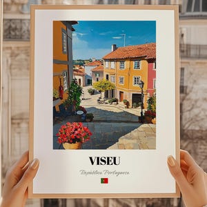Könnte beinhalten: Ein gerahmter Druck einer Straßenszene in Viseu, Portugal. Das Kunstwerk zeigt farbenfrohe Gebäude mit orangefarbenen Ziegeldächern, eine Kopfsteinpflasterstraße und rote Blumen. Der Druck enthält den Text "VISEU" und "República Portuguesa" mit der portugiesischen Flagge.