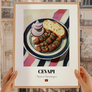May include: A framed print featuring a plate of cevapi, a Balkan dish, with bread and sliced red onion. The plate sits on a striped cloth. The print has the word "CEVAPI" and "Made in Montenegro" printed on it.