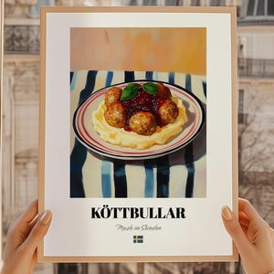 Puede incluir: Un póster enmarcado con albóndigas suecas, Köttbullar, servidas con puré de patatas y salsa de arándanos rojos. El plato está sobre un mantel a rayas. El póster incluye la palabra "KÖTTBULLAR" y "Made in Sweden".