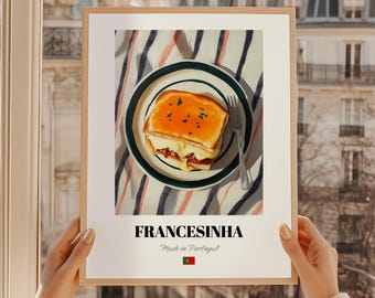 May include: A framed print featuring a Francesinha sandwich on a plate with a fork. The sandwich has melted cheese and a golden-brown sauce. The plate rests on a striped tablecloth. The print includes the word "FRANCESINHA" and "Made in Portugal".