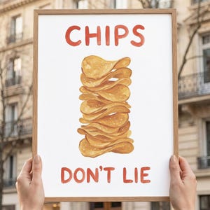 Könnte beinhalten: Ein gerahmter Druck mit den roten Worten "CHIPS DON'T LIE" über und unter einem Stapel goldbrauner Kartoffelchips. Das Kunstwerk wird von zwei Händen gehalten, mit einem verschwommenen Hintergrund im Freien.