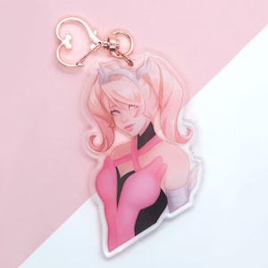 May include: A pink and white anime-style character keychain with a heart-shaped ring. The character has long blonde hair, pink eyes, and is wearing a pink and black dress.