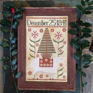 May include: A framed cross-stitch sampler with a white sheep carrying a Christmas tree on its back. The sampler is dated "December 25, 1841" and features a red, white, and green color scheme.