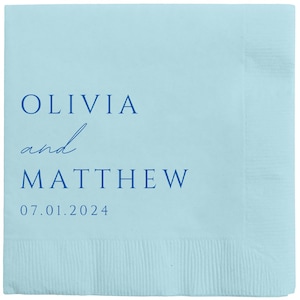 May include: Light blue paper napkin with the text "Olivia and Matthew" in blue lettering and the date "07.01.2024" printed below.