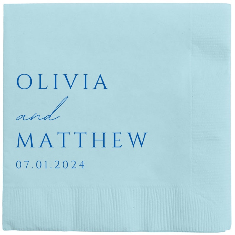 May include: Light blue paper napkin with the text "Olivia and Matthew" in blue lettering and the date "07.01.2024" printed below.