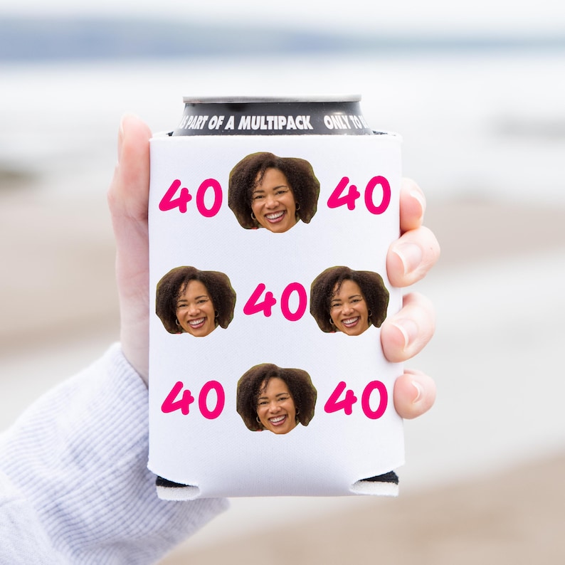 May include: White can cooler with a black top and the text "Part of a Multipack Only to" printed on the top. The cooler has a repeated pattern of a woman's face and the number "40" printed in pink.