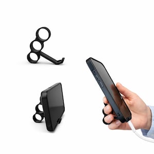 May include: Black phone grip with three finger holes and a kickstand. The phone grip is shown in three different views: detached, attached to a phone, and holding a phone with a charging cable.