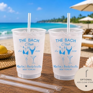 Może przedstawiać: Dwa matowe plastikowe kubki z białymi słomkami, każdy z niebieskim napisem THE BACH Club Est 2026, Martin's Bachelorette, NEW YORK, NY oraz grafiką dw&oacute;ch bikini na sznurku do bielizny i kieliszkiem do martini, z dwiema dodatkowymi słomkami.