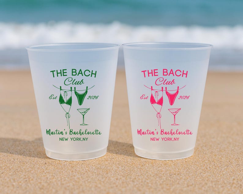 Może przedstawiać: Dwa kubki z matowego plastiku z napisem THE BACH CLUB, Est 2026, Martin's Bachelorette oraz NEW YORK, NY. Jeden kubek ma zielony nadruk, drugi r&oacute;żowy. Oba przedstawiają grafikę dw&oacute;ch bikini na sznurku do bielizny oraz kieliszek do martini.