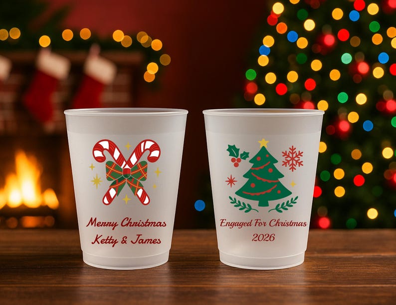 May include: Two frosted plastic cups. The left cup features red and white candy canes, a green plaid bow, and the text "Merry Christmas Ketty & James". The right cup displays a green Christmas tree, holly, and "Engaged For Christmas 2026".