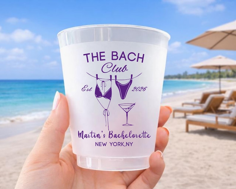 Może przedstawiać: P&oacute;łprzezroczysty plastikowy kubek z fioletowym tekstem i grafikami. Projekt zawiera napisy THE BACH CLUB, Est 2026, Martin's Bachelorette oraz NEW YORK, NY, a także ilustracje bikini, fig od stroju kąpielowego oraz kieliszka do martini.