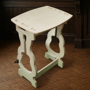 Peut inclure: Une table d'appoint en bois vert clair avec un plateau rectangulaire et des pieds incurvés décoratifs. La table a une manivelle sur le côté et mesure environ 61 cm de long, 46 cm de large et 71 cm de haut.