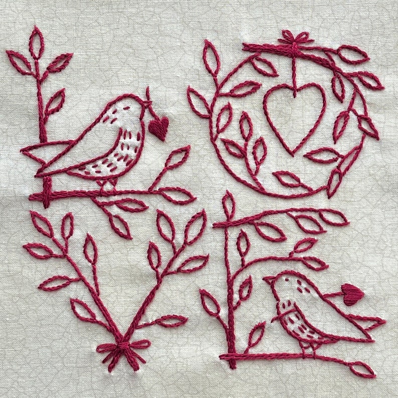 May include: Embroidered design of the word "love" with two birds and hearts. The design is done in a dark red thread on a white fabric.