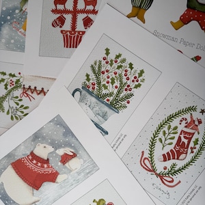 May include: A selection of Christmas-themed art prints with watercolour illustrations. Designs include a Christmas tree, polar bears, holly in a teacup, a stocking, and a snowman. The prints have a whimsical, festive aesthetic.