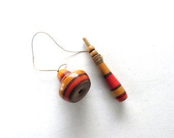 May include: A vintage wooden spinning top toy with a matching handle. The top is painted with alternating bands of orange, red, and brown. The handle is also striped with red and brown. A thin string is attached to the top.