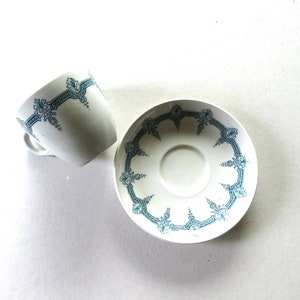May include: A white teacup and saucer with a blue and white floral pattern. The cup and saucer are both decorated with a delicate floral design.