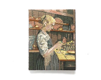 May include: A tapestry depicting a woman in a kitchen setting. She is wearing a white blouse and a dark apron, working at a table. The background shows shelves with various kitchen items, rendered in muted tones.