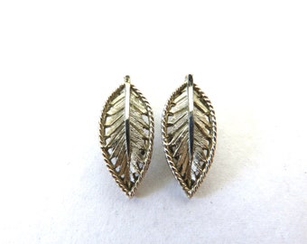 May include: A pair of silver tone leaf-shaped earrings with a delicate filigree design.