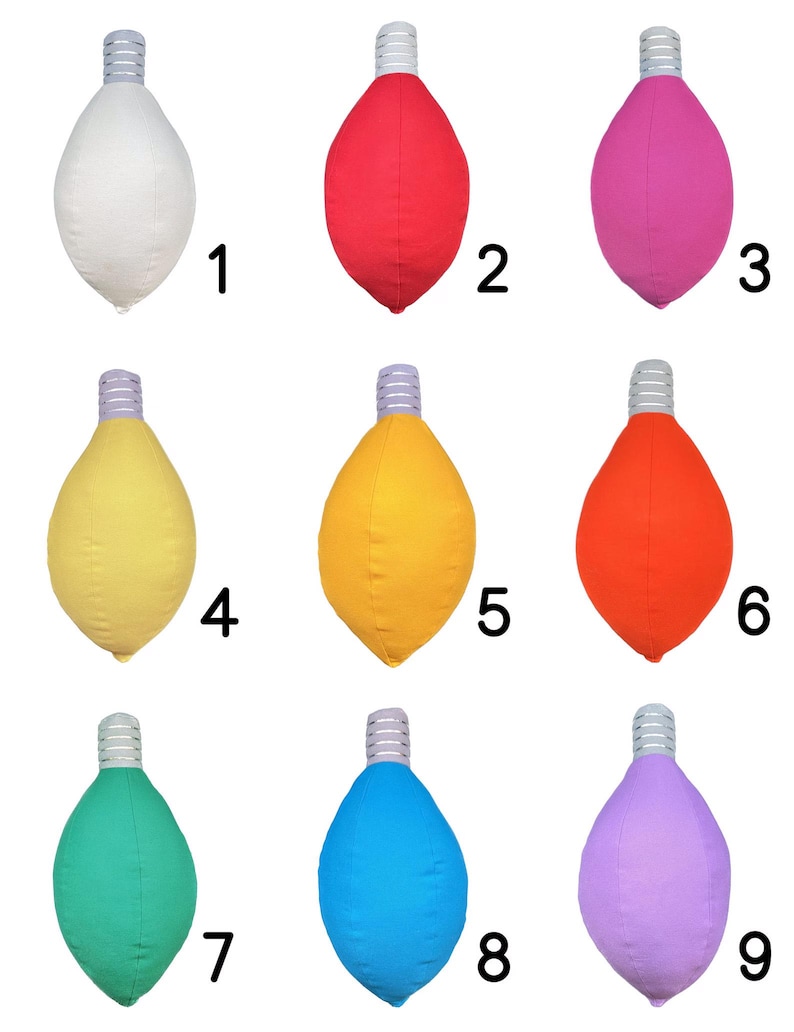 May include: Nine light bulb shaped pillows in different colors: white, red, pink, yellow, orange, green, blue, and purple. The pillows are arranged in three rows of three.