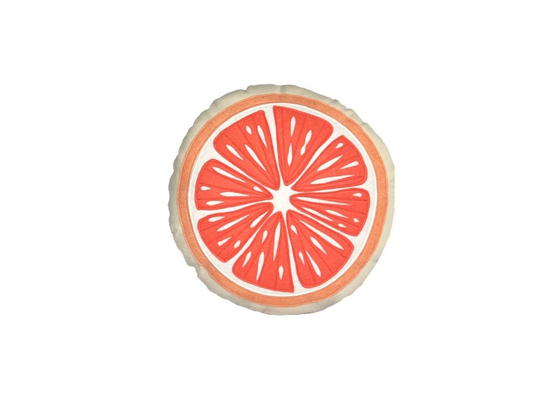 May include: A round, white pillow with a red grapefruit slice design. The pillow is perfect for adding a pop of color and a touch of whimsy to any room.