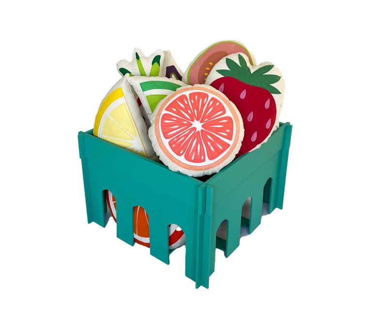 May include: A teal green crate filled with colorful fruit-shaped pillows. The pillows are shaped like a lemon, lime, grapefruit, strawberry, and guava.