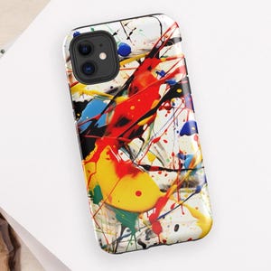 May include: A phone case with a colorful abstract design featuring splashes of red, yellow, blue, and black paint on a white background.