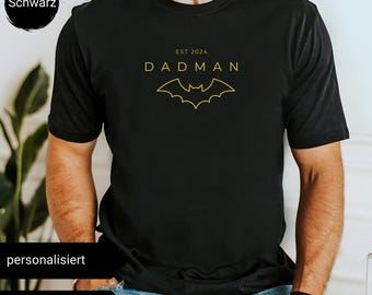 Puede incluir: Camiseta negra con un gráfico de murciélago amarillo y el texto "DADMAN EST 2024".